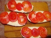 На намазанные половинки булочек выкладываем слоем шайбы помидоров