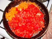 В сковороду влить масло, всыпать помидоры, лук и морковь и поставить на огонь